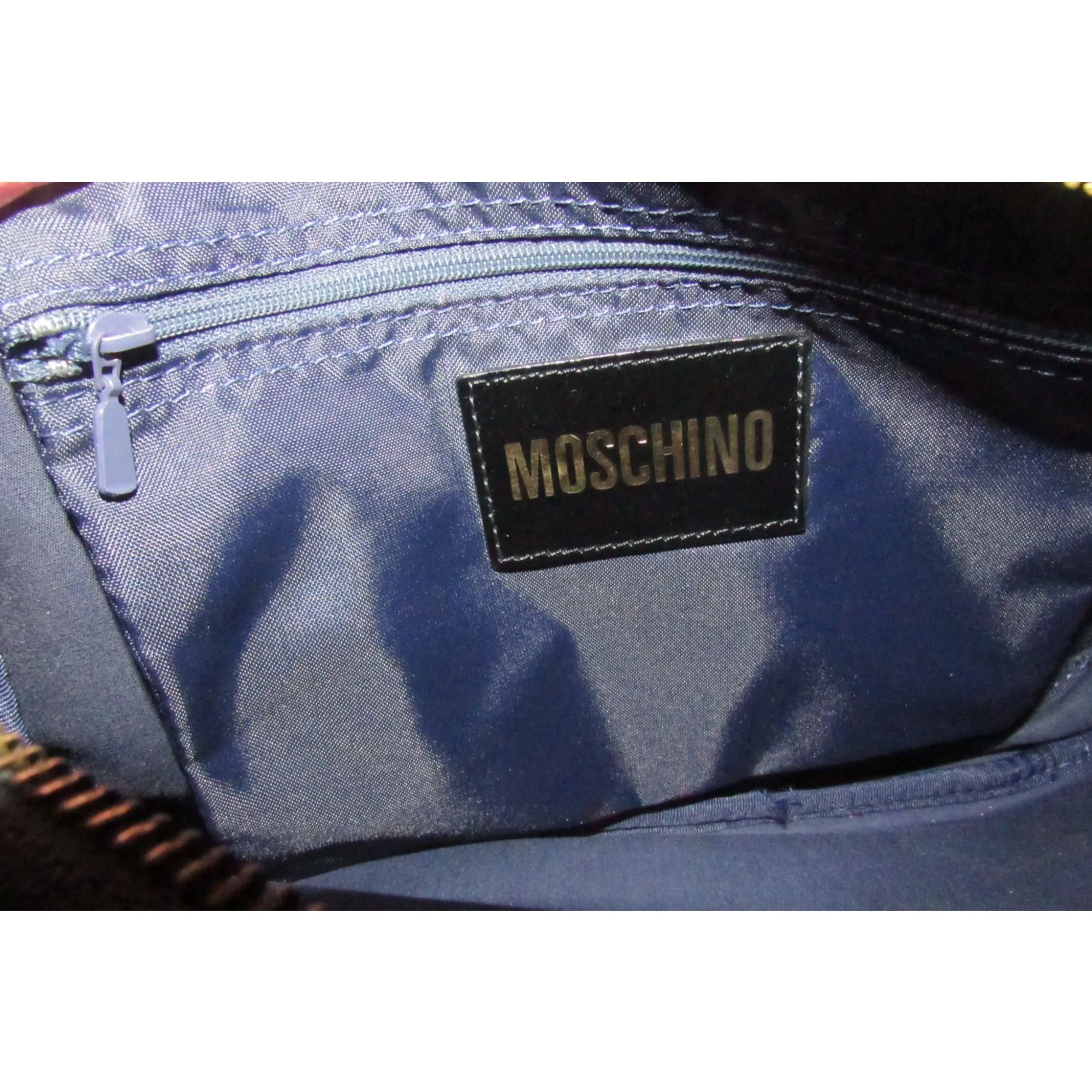 Moschino, black canvas & leather, cross body with a zip top, bold, gold, MOSCHINO letter accents, & a long strap with snaps on both sides