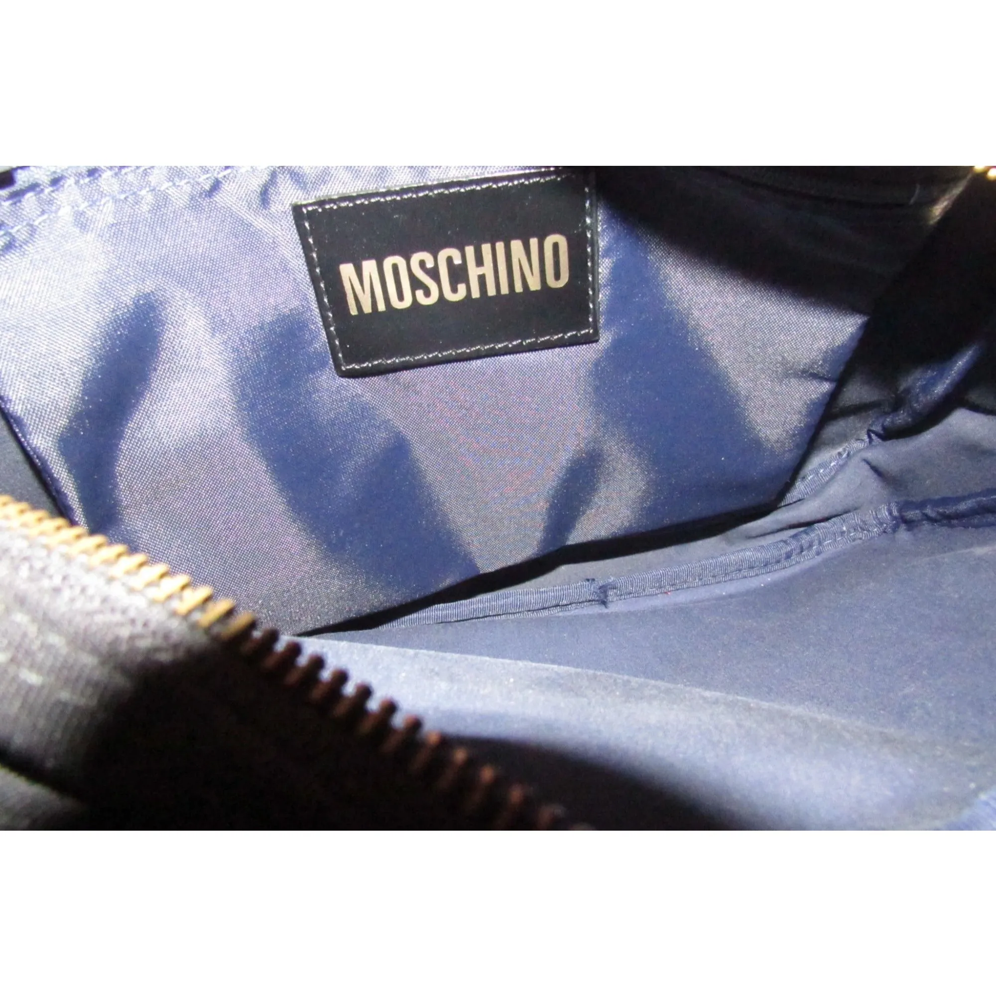 Moschino, black canvas & leather, cross body with a zip top, bold, gold, MOSCHINO letter accents, & a long strap with snaps on both sides