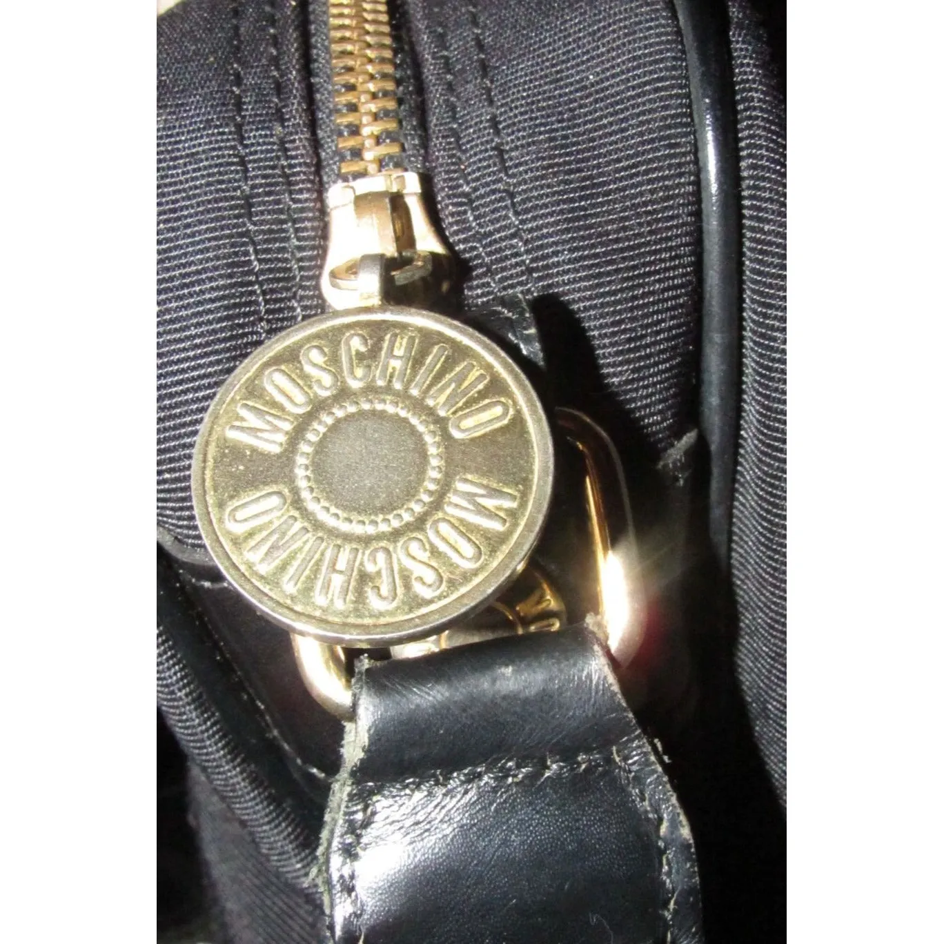 Moschino, black canvas & leather, cross body with a zip top, bold, gold, MOSCHINO letter accents, & a long strap with snaps on both sides