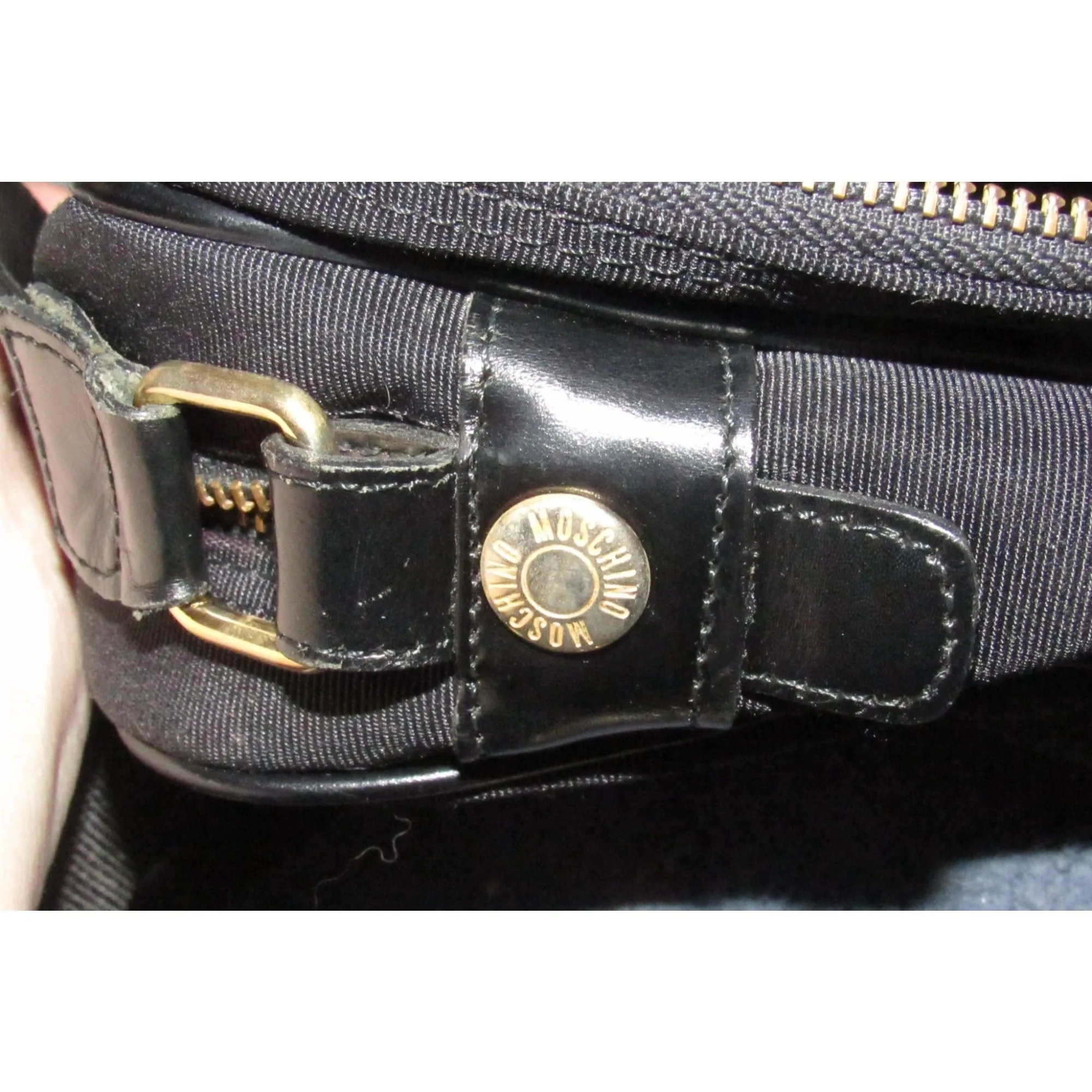 Moschino, black canvas & leather, cross body with a zip top, bold, gold, MOSCHINO letter accents, & a long strap with snaps on both sides